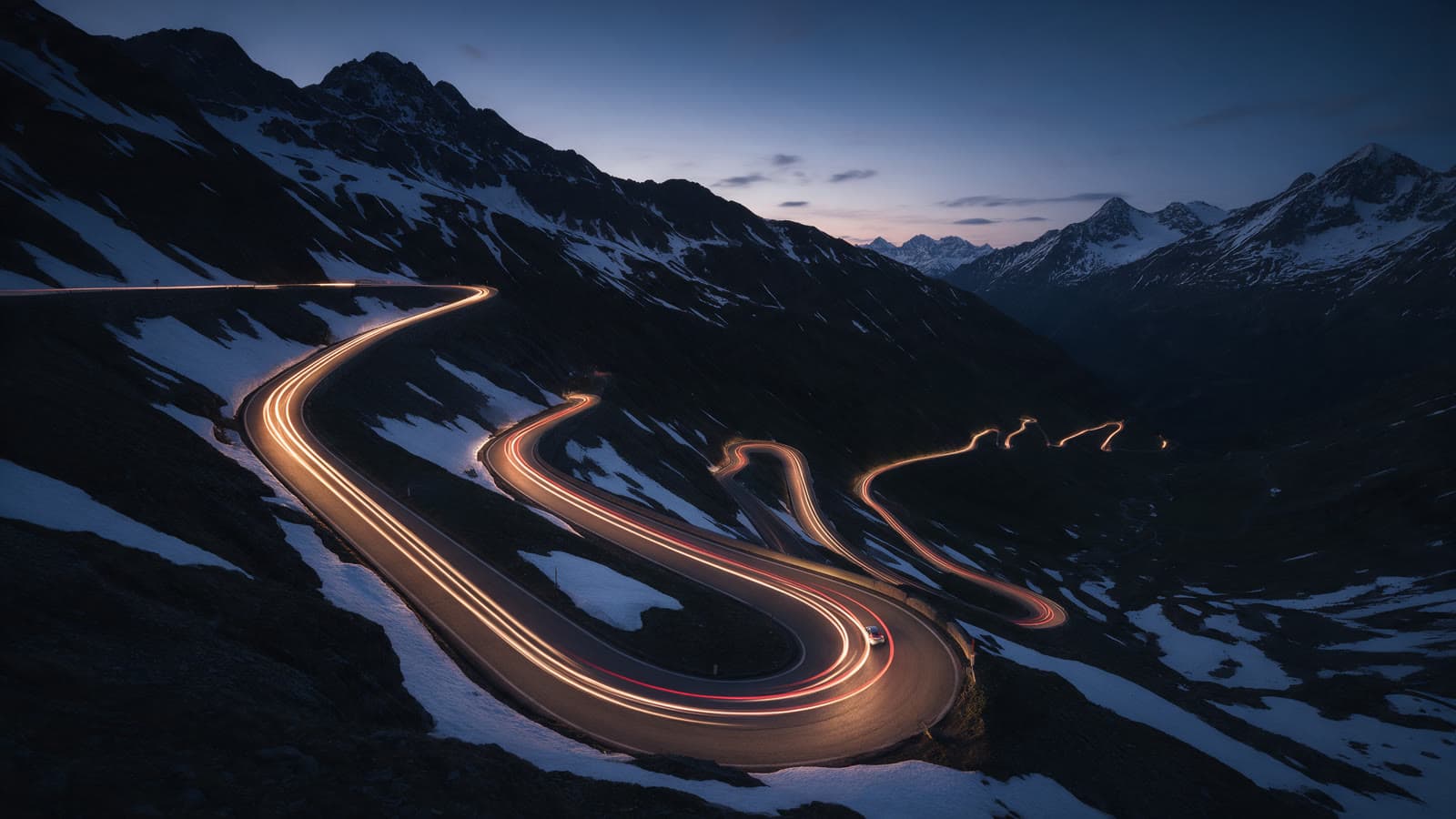 A slow aerial move at blue hour with headlights tracing the road.